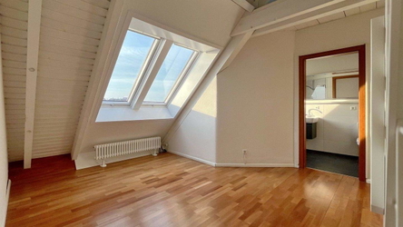 Schlafzimmer mit großen Dachfenstern, sichtbaren Holzbalken und angrenzendem Bad