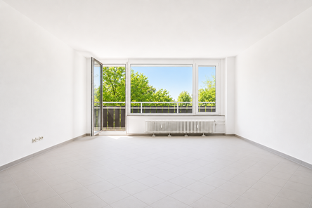 Lichtdurchfluteter Wohnbereich mit großer Fensterfront, sonniger Süd-West-Ausrichtung und direktem Zugang zum Balkon mit schönem Grünblick.