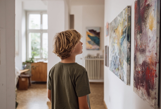 Ein Kind bewundert ein Kunstwerk an der Wand.