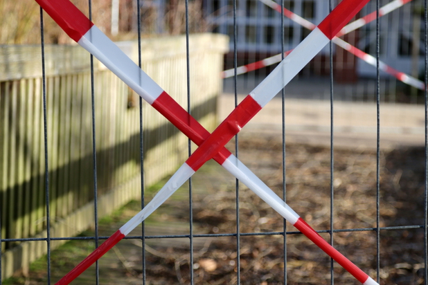 Ein Zaun, vor welchem rot-weißes Absperrband ist. 
