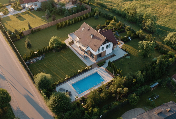 Ein bebautes Grundstück mit Garten und Pool aus der Luft fotografiert.