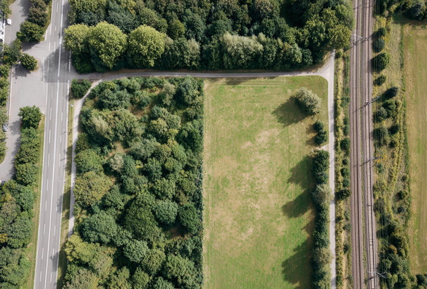 Aus Vogelperspektive ein Grundstück zwischen einer Landstraße und einem Bahngleis.