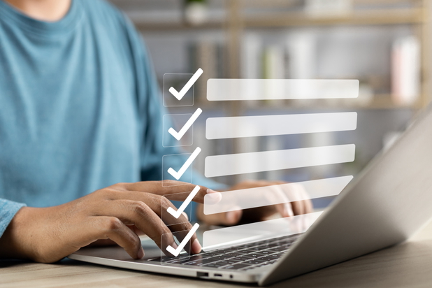 Eine Person sitzt an einem Laptop, darüber ist eine Liste mit Haken digital hinzugefügt.