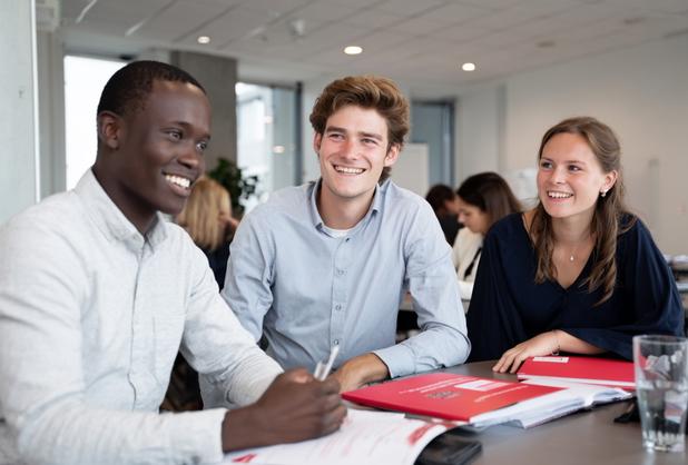 Einige junge Erwachsene sitzen gemeinsam in einem Seminarraum für die Immobilienmakler Ausbildung.