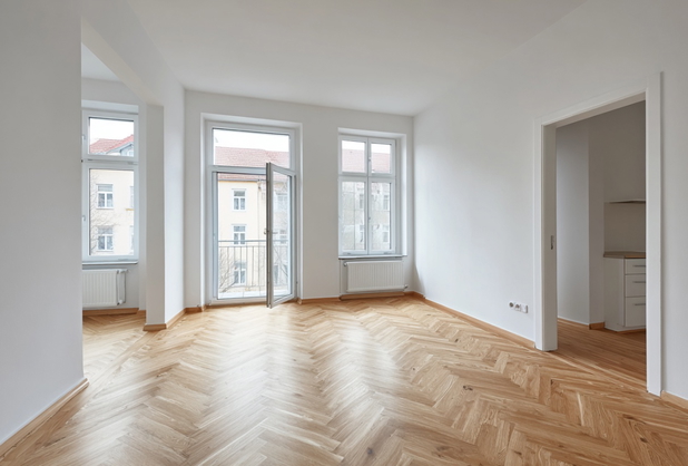 Eine leere helle Wohnung mit Parkettboden.