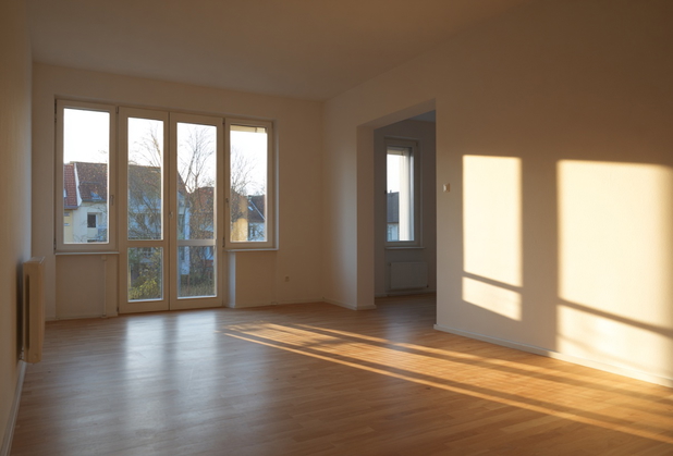 Eine leerstehende Wohnung mit Parkettboden bei Sonnenuntergang.