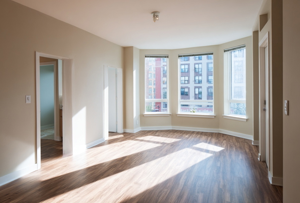 Ein Zimmer in einer modernisierten Wohnung mit mehreren Fenstern raus zur Straße.