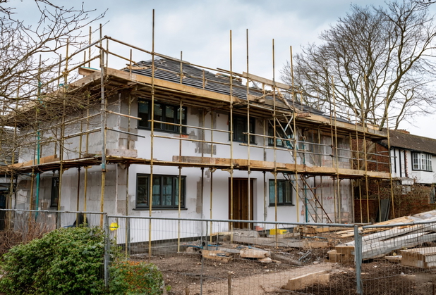 Ein Haus in der Bauphase umzingelt von Baugerüst.