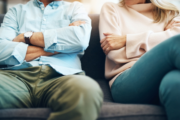 Pärchen sitzt mit verschränkten Armen auf der Couch