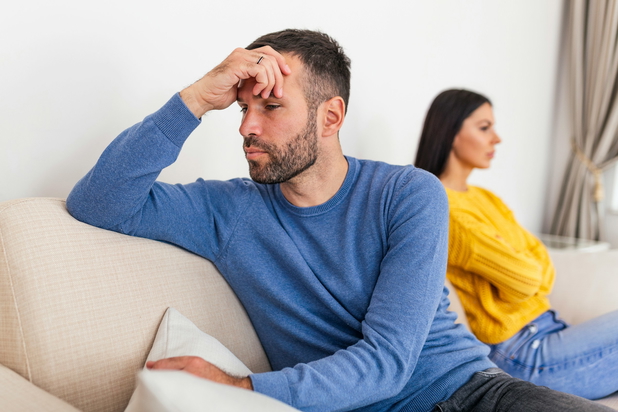 Mann und Frau sitzen schlecht gelaunt von einander abgewandt auf einer Couch.