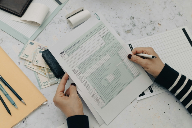 Eine Person hält einen Stift in der Hand und füllt ein Papier aus.