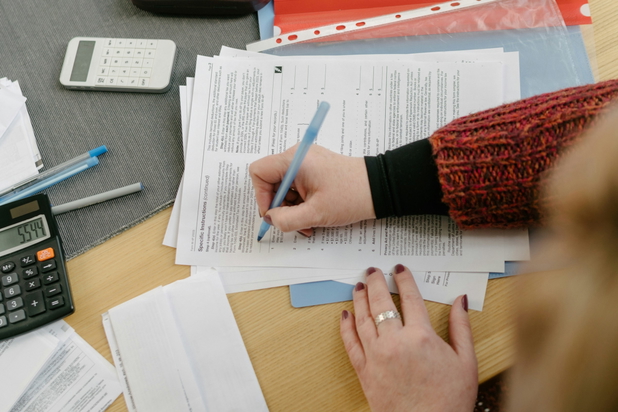 Frau mit Stift in der Hand füllt Steuerpapiere aus.