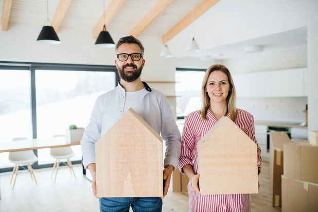 Mann und Frau stehen nebeneinander und haben Häuser aus Holz in der Hand.