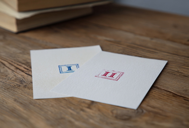 Auf zwei Papieren sind zwei verschiedene Stempel, auf dem linken Blatt eine 1, auf dem rechten Blatt eine 2.