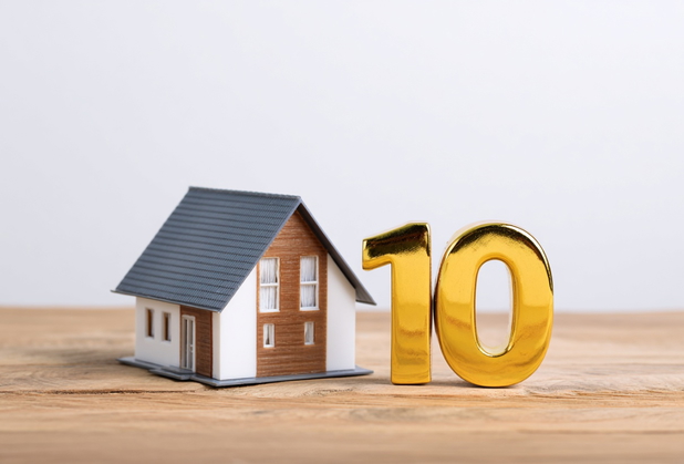 Neben einem Miniaturhaus ist eine goldene Zehn zu sehen.