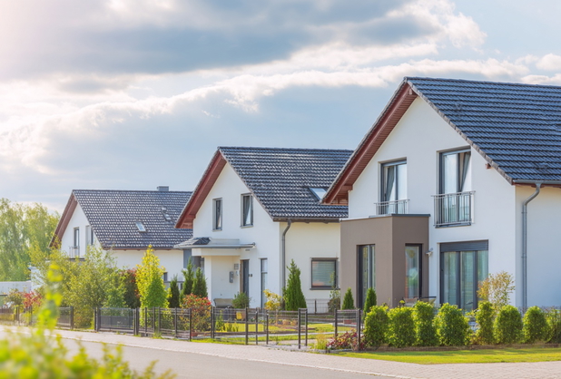 Drei ähnliche moderne Einfamilienhäuser mit Gärten.