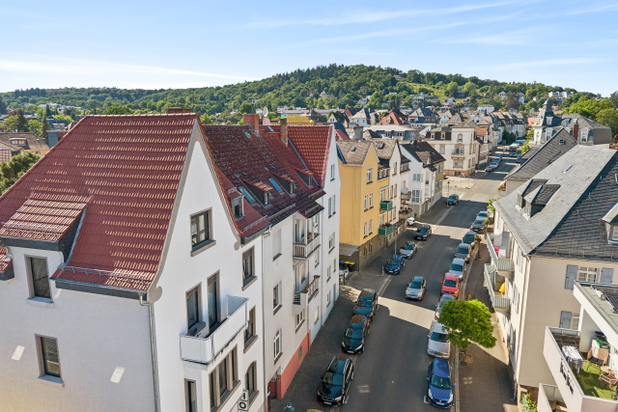 Luftaufnahme von einem Referenzobjekt von apollo living: Straße mit Häusern und Wald im Hintergrund.