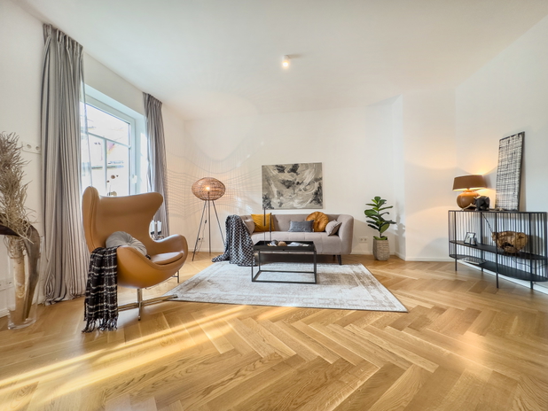 Modernes helles Wohnzimmer mit Couch und Sessel.