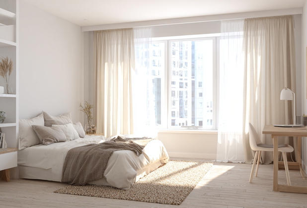 Schlafzimmer in hellen Tönen gehalten mit großer Fensterfront, großem Bett, Schreibtisch und Stuhl.