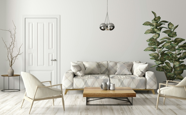 Ein Wohnzimmer mmit Couch und Sesseln, alle in weiß gekleidet, in der Mitte ein hölzerner Couchtisch, neben der Couch eine Pflanze.