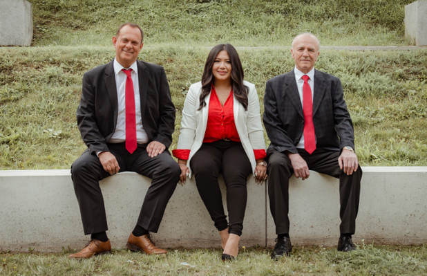 Drei Personen vom Team der Hassel Immobilien GmbH sitzen auf einer Mauer.