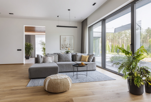 Ein modern eingerichtetes Wohnzimmer mit grauer Couch und mehreren Pflanzen.