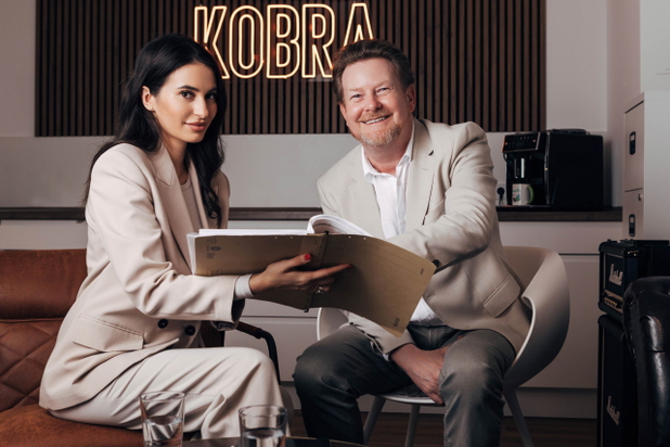 Mitarbeiter von KOBRA Immobilien sitzen nebeneinander mit einem Heft in der Hand.