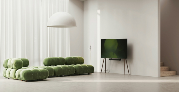Ein geräumiges und modernes Wohnzimmer mit einem Flachbildferseher und einer grünen Designer-Couch.