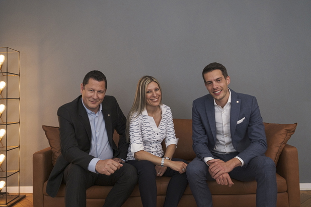 Das Team von Lehmann Hueber Immobilien (drei Personen) sitzt auf einer braunen Couch vor einer grauen Wand.
