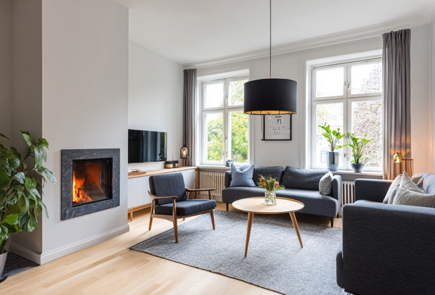 Ein Wohnzimmer mit Kamin und dunkelgrauen Sitzmöbeln.