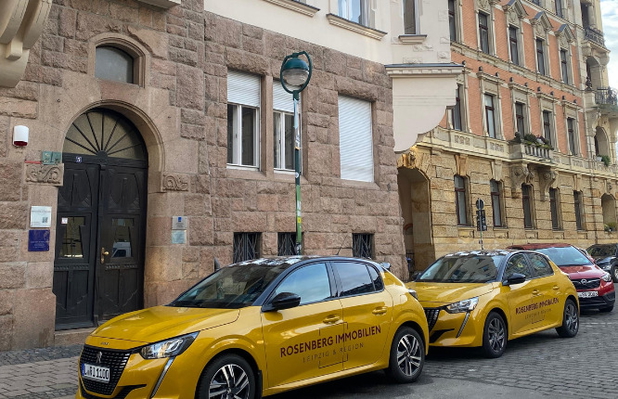 Autos von Rosenberg Immobilien vor einem Gebäude.
