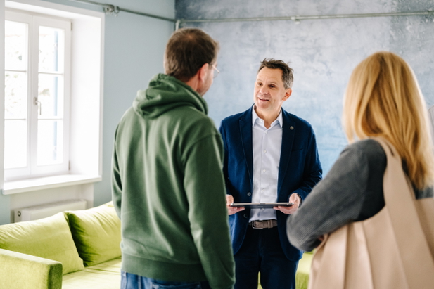 Immobilienmakler von Schneider & Prell mit zufriedenen Kunden bei einer Besichtigung.