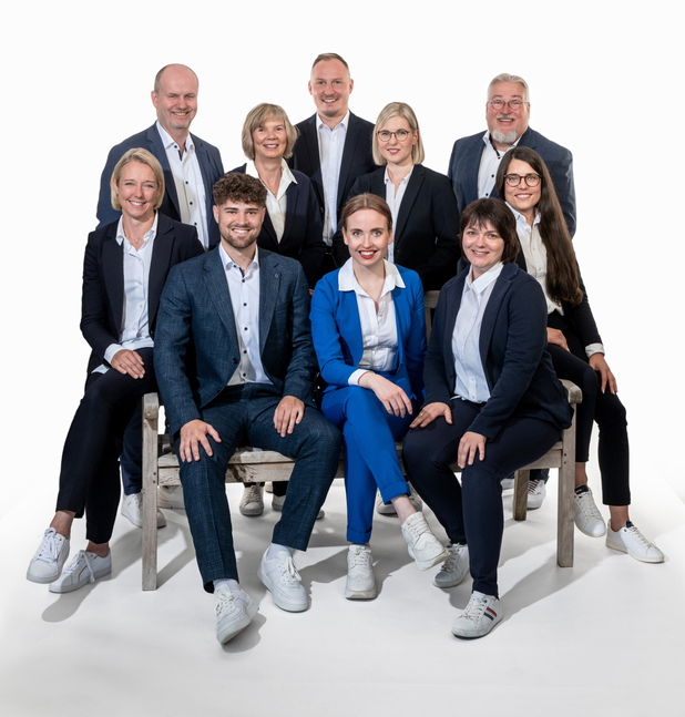 Teamphoto von Volksbank Raiffeisenbank eG Immobilien vor weißer Wand.