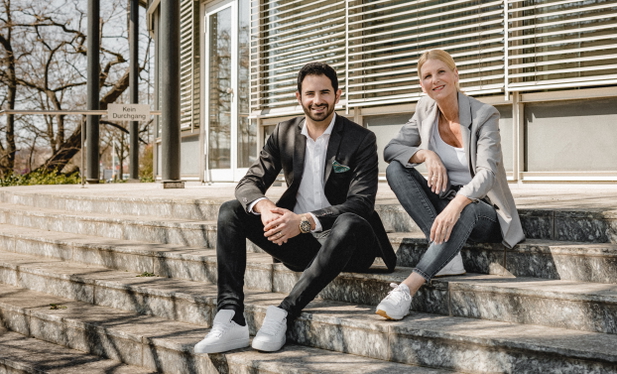 Gründer Meric Kilic und seine Kollegin auf Stufen sitzend.