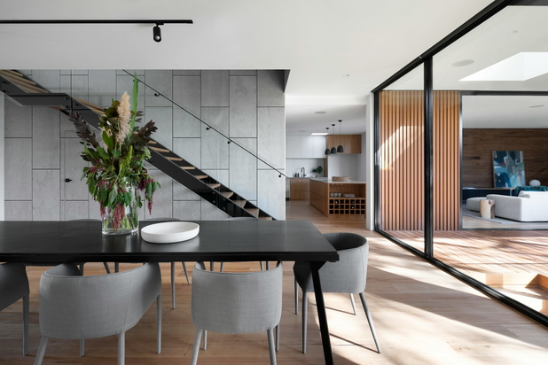 Blick in ein modernes Wohnzimmer mit Esstisch und Glaswand.